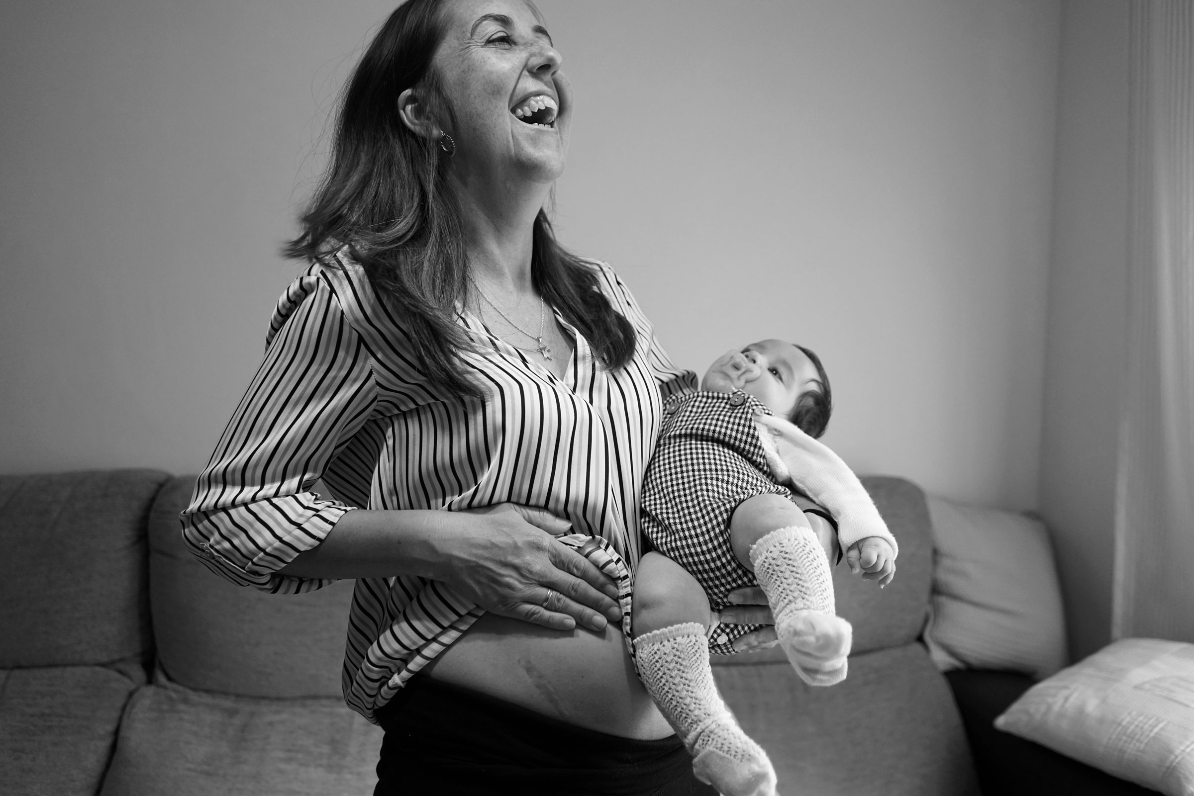 María, 41 años. Muestra en su domicilio la cicatriz del trasplante renal años después de la cirugía. Su madre fue la donante. En brazos sostiene a su hijo, nacido tras el trasplante.